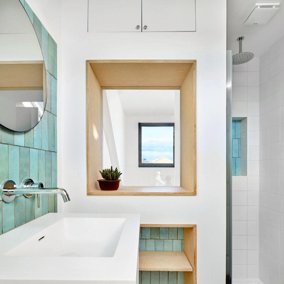 На фото: главная ванная комната среднего размера в современном стиле с белыми фасадами, открытым душем, инсталляцией, зеленой плиткой, керамической плиткой, белыми стенами, полом из керамогранита, монолитной раковиной, белым полом, душем с распашными дверями, белой столешницей, нишей, тумбой под одну раковину и подвесной тумбой