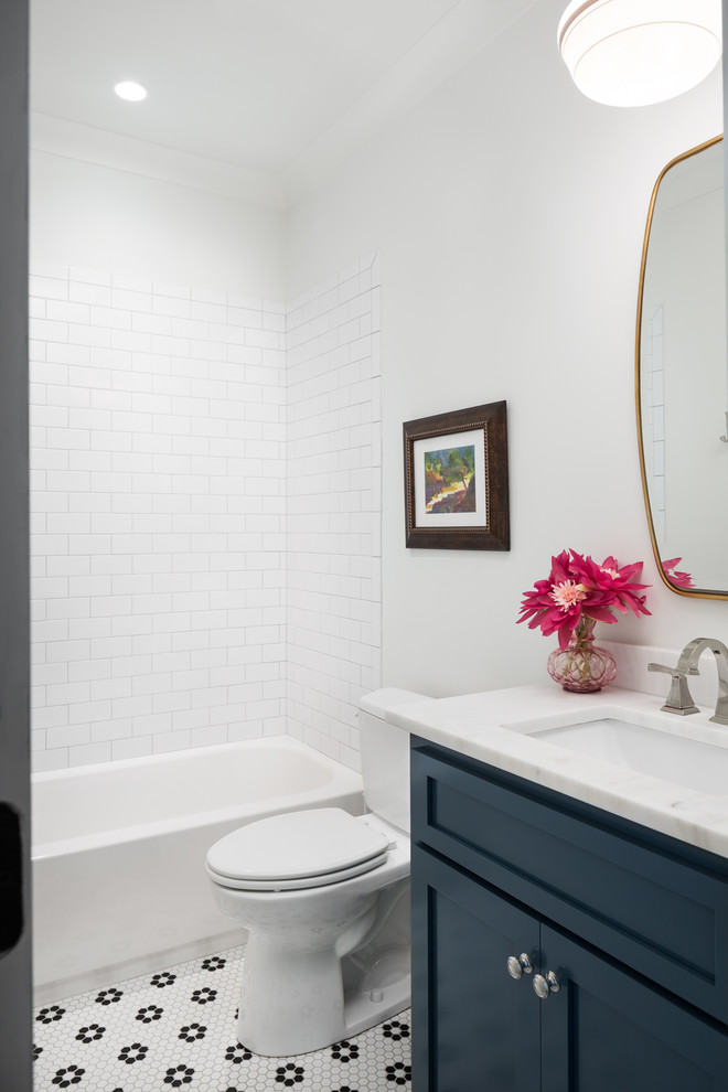 Стильный дизайн: ванная комната среднего размера в стиле кантри с фасадами с утопленной филенкой, синими фасадами, ванной в нише, душем над ванной, раздельным унитазом, белой плиткой, керамической плиткой, белыми стенами, полом из керамической плитки, врезной раковиной, мраморной столешницей, черным полом и шторкой для ванной - последний тренд