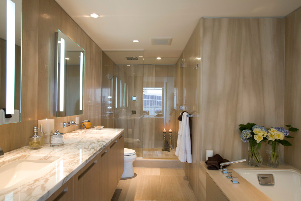 Immagine di una stanza da bagno design con lavabo sottopiano, ante lisce, ante in legno scuro, vasca sottopiano, doccia alcova e piastrelle beige