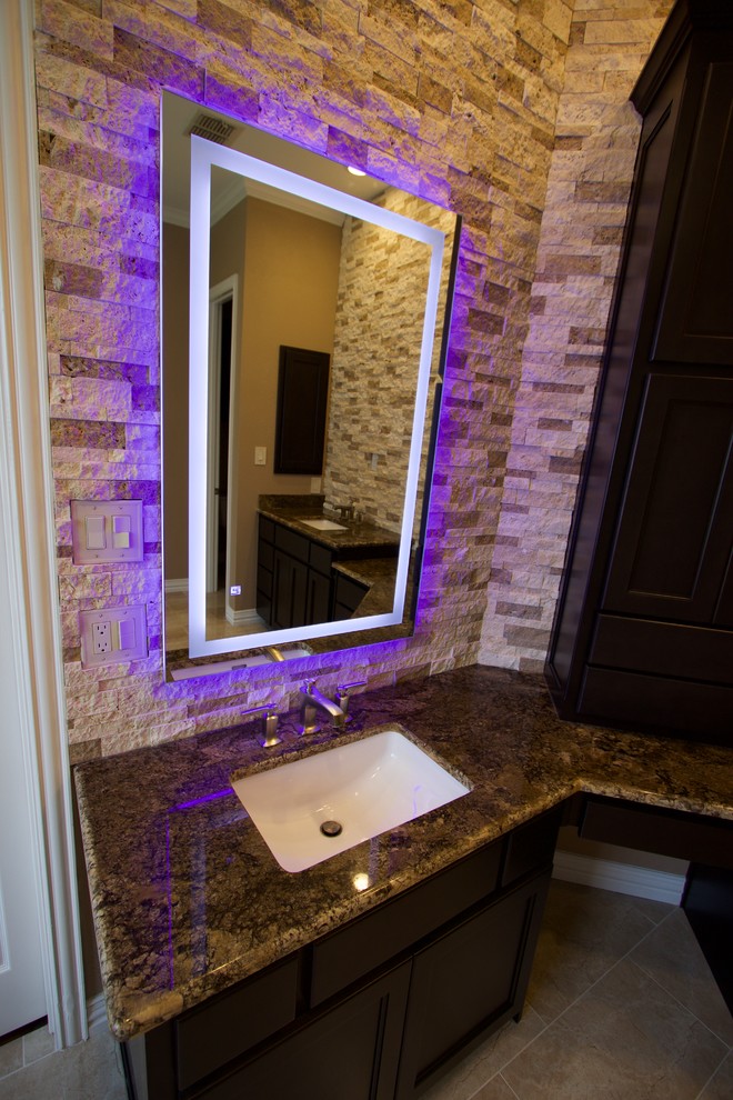 Example of a large transitional master ceramic tile and beige floor bathroom design in Dallas with recessed-panel cabinets, dark wood cabinets, brown walls, an undermount sink, granite countertops and a hinged shower door