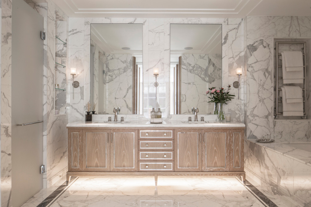 Modelo de cuarto de baño clásico de tamaño medio con puertas de armario de madera clara, encimera de mármol, bañera encastrada, ducha abierta, paredes blancas y suelo de mármol