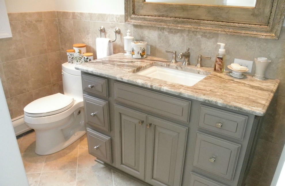 Inspiration for a medium sized traditional ensuite bathroom in New York with raised-panel cabinets, grey cabinets, a built-in bath, an alcove shower, a two-piece toilet, beige tiles, glass tiles, beige walls, ceramic flooring, a submerged sink, granite worktops, beige floors and a hinged door.