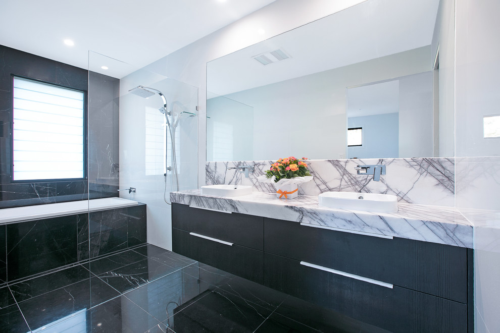 Inredning av ett modernt stort grå grått en-suite badrum, med släta luckor, svarta skåp, en öppen dusch, svart och vit kakel, vita väggar, ett fristående handfat, svart golv, med dusch som är öppen, klinkergolv i keramik, bänkskiva i kvarts, en toalettstol med separat cisternkåpa och keramikplattor