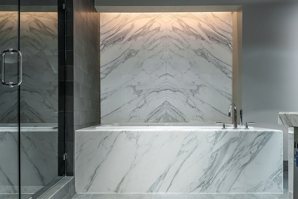 This is an example of a contemporary bathroom in Houston with a freestanding bath and stone slabs.