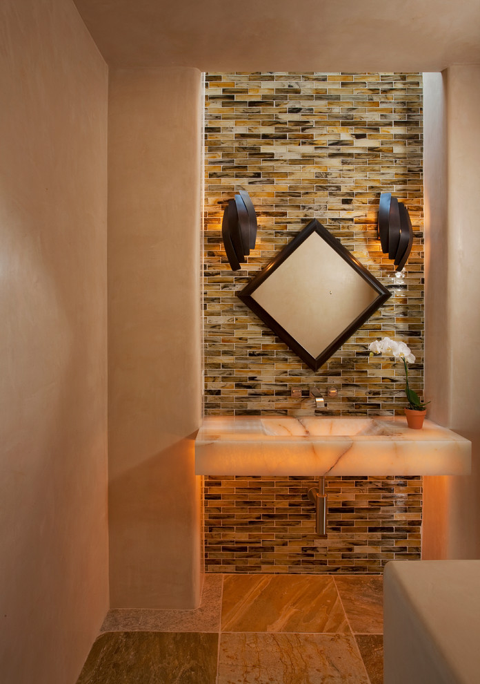 На фото: ванная комната в средиземноморском стиле с подвесной раковиной, разноцветной плиткой и стеклянной плиткой с