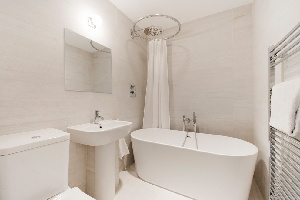 Cette image montre une salle de bain design de taille moyenne pour enfant avec une baignoire indépendante, un combiné douche/baignoire, WC à poser, un carrelage gris, des carreaux de porcelaine, un mur gris, un sol en carrelage de porcelaine, un lavabo de ferme, un sol gris et une cabine de douche avec un rideau.