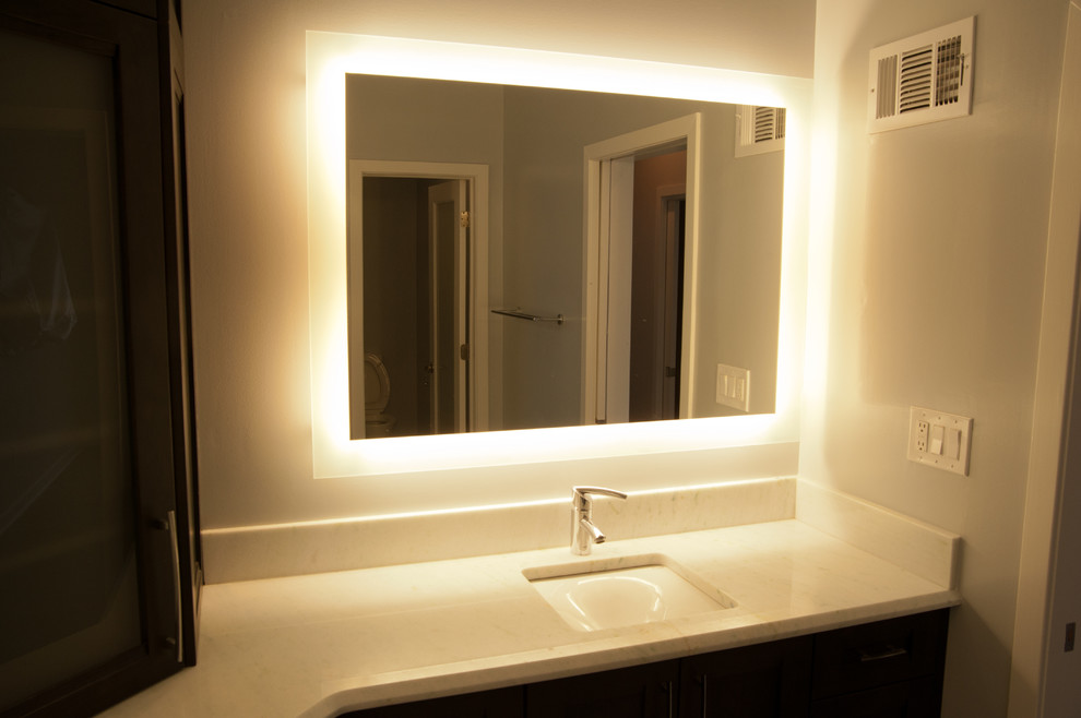 Réalisation d'une salle de bain principale design en bois foncé de taille moyenne avec un placard à porte shaker, un mur blanc, un lavabo encastré et un plan de toilette en marbre.