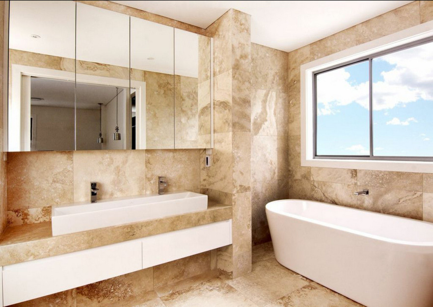 Example of a large minimalist master beige tile and stone tile limestone floor freestanding bathtub design in Sydney with a trough sink, glass-front cabinets, white cabinets, limestone countertops and beige walls