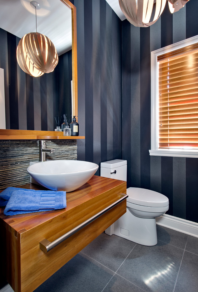 Aménagement d'une petite salle d'eau contemporaine en bois brun avec une vasque, un placard à porte plane, WC à poser, un carrelage gris, des carreaux de porcelaine, un sol en carrelage de porcelaine, un plan de toilette en bois, un mur bleu et un plan de toilette marron.