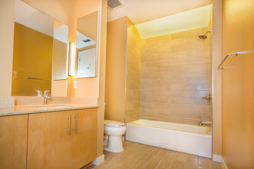 Cette photo montre une salle de bain principale tendance en bois clair avec un lavabo encastré, un placard à porte plane, une baignoire en alcôve, un combiné douche/baignoire, WC à poser, un carrelage beige, un carrelage métro et un mur beige.
