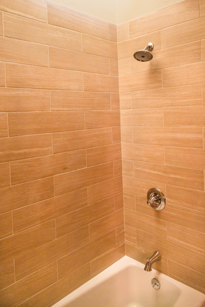 Foto di una stanza da bagno padronale minimal con lavabo sottopiano, ante in legno chiaro, vasca/doccia, WC monopezzo, piastrelle beige e piastrelle diamantate