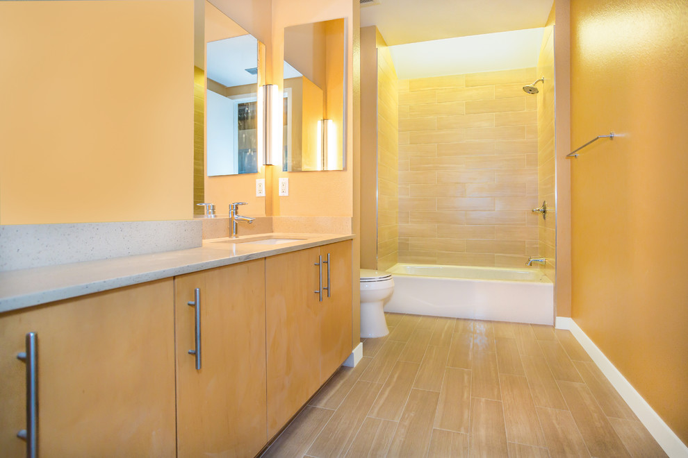 На фото: главная ванная комната в современном стиле с врезной раковиной, плоскими фасадами, светлыми деревянными фасадами, ванной в нише, душем над ванной, унитазом-моноблоком, бежевой плиткой, плиткой кабанчик и бежевыми стенами с