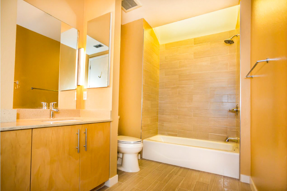 Cette photo montre une salle de bain principale tendance en bois clair de taille moyenne avec un placard à porte plane, une baignoire en alcôve, un combiné douche/baignoire, un carrelage beige, un carrelage métro et un sol beige.