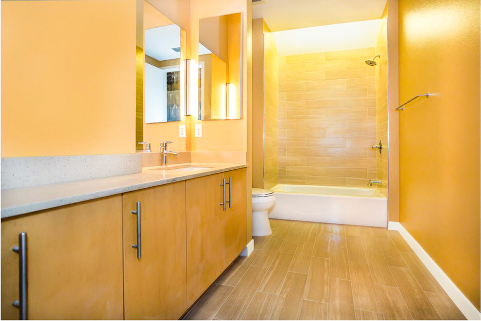 Diseño de cuarto de baño principal actual de tamaño medio con armarios con paneles lisos, puertas de armario de madera clara, bañera empotrada, combinación de ducha y bañera, baldosas y/o azulejos beige, baldosas y/o azulejos de cemento y suelo beige