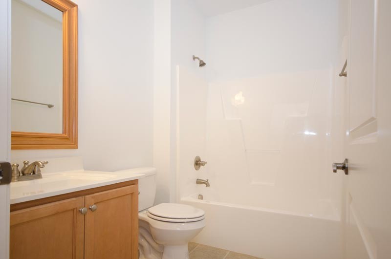 Example of a trendy tub/shower combo design in Raleigh with an integrated sink, dark wood cabinets and a two-piece toilet