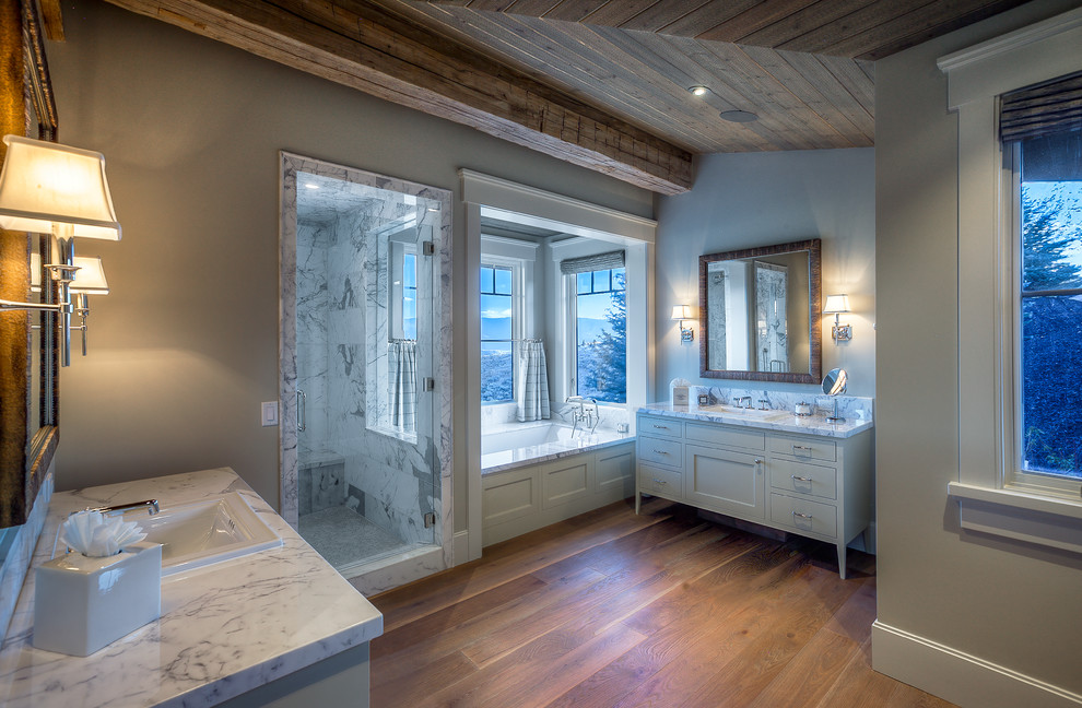 Inredning av ett klassiskt stort vit vitt en-suite badrum, med möbel-liknande, gröna skåp, ett platsbyggt badkar, en hörndusch, vit kakel, stenhäll, gröna väggar, mellanmörkt trägolv, ett nedsänkt handfat, marmorbänkskiva och dusch med gångjärnsdörr
