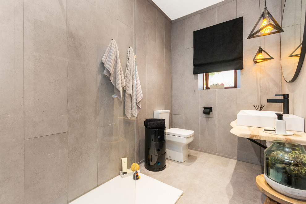 На фото: ванная комната среднего размера в современном стиле с открытым душем, раздельным унитазом, серой плиткой, серыми стенами, настольной раковиной, столешницей из дерева, серым полом, открытым душем и бежевой столешницей