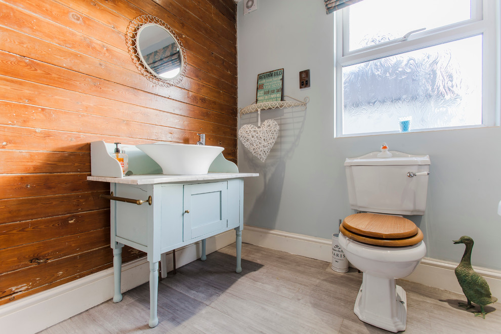 Idéer för ett lantligt badrum, med möbel-liknande, blå skåp, en toalettstol med separat cisternkåpa, blå väggar och ljust trägolv