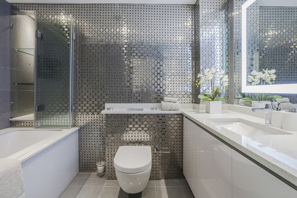 Пример оригинального дизайна: главная ванная комната в современном стиле с плоскими фасадами, белыми фасадами, полновстраиваемой ванной, инсталляцией, металлической плиткой, врезной раковиной и серым полом