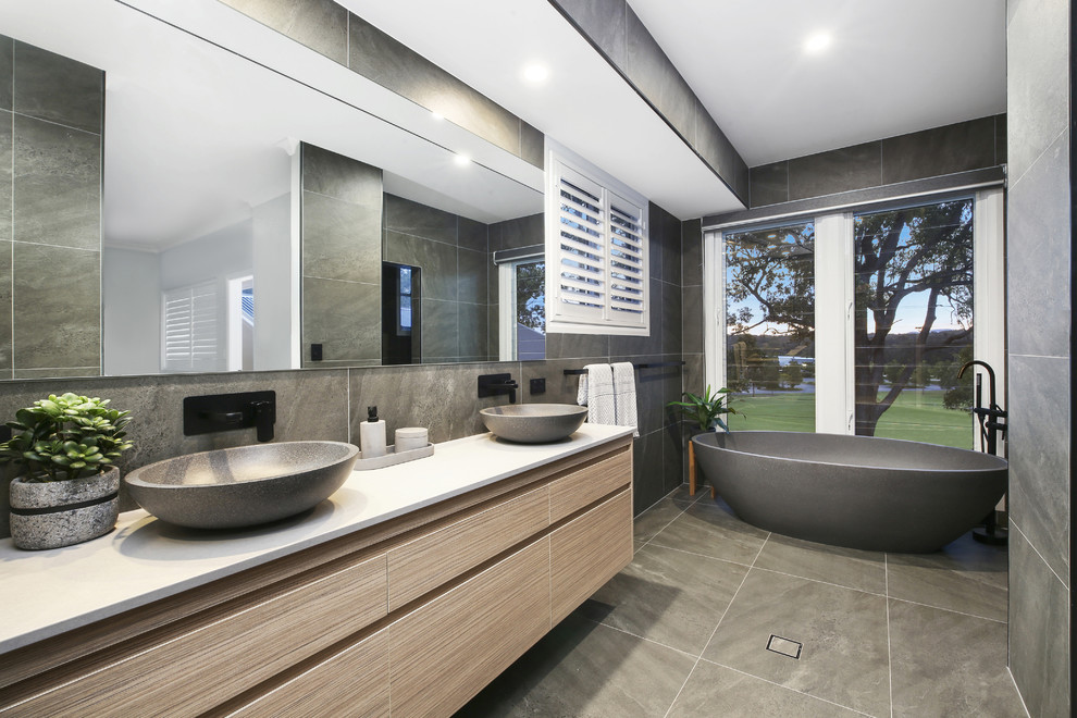 Foto di una stanza da bagno con vasca freestanding, pareti grigie, top in quarzo composito, pavimento grigio e top bianco