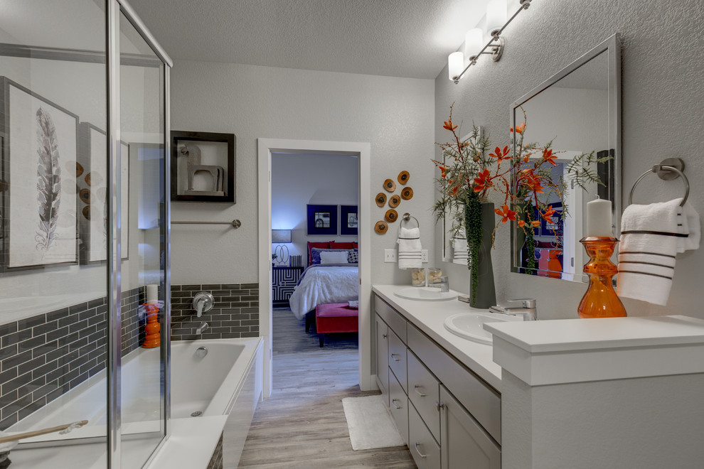 Foto di una stanza da bagno padronale tradizionale con ante in stile shaker, ante grigie, vasca ad angolo, piastrelle grigie, pareti grigie, lavabo da incasso e pavimento grigio