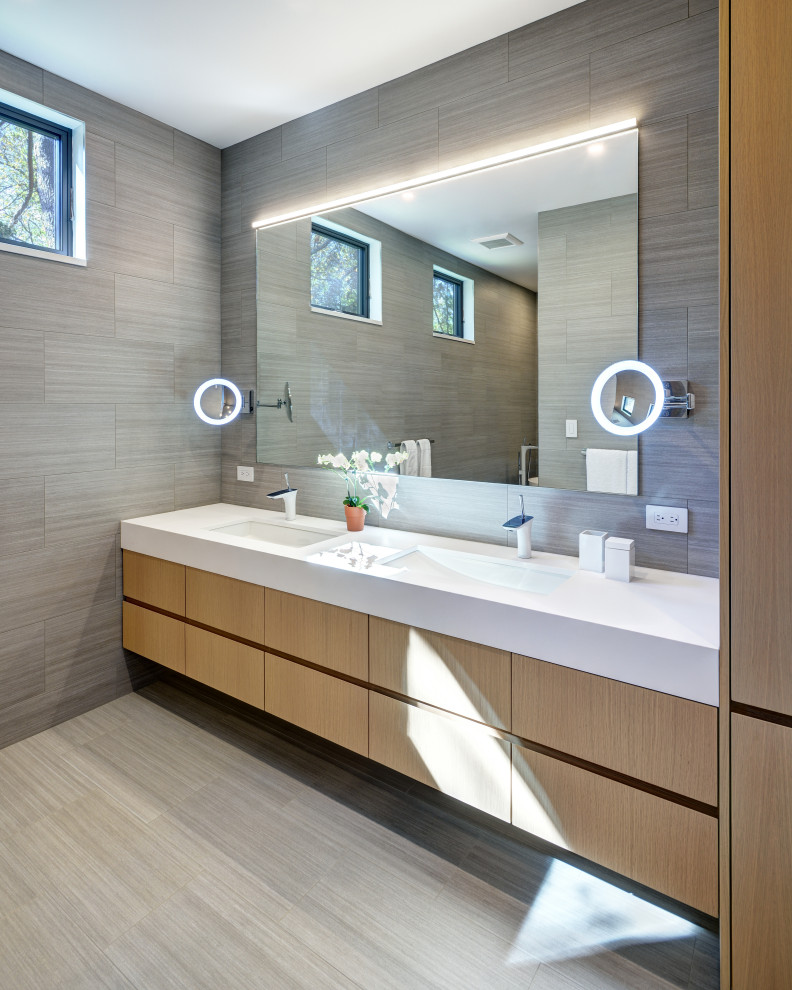 Large contemporary ensuite bathroom in New York with medium wood cabinets, a freestanding bath, a walk-in shower, a one-piece toilet, grey tiles, ceramic tiles, grey walls, ceramic flooring, a wall-mounted sink, engineered stone worktops, grey floors, an open shower, white worktops and flat-panel cabinets.