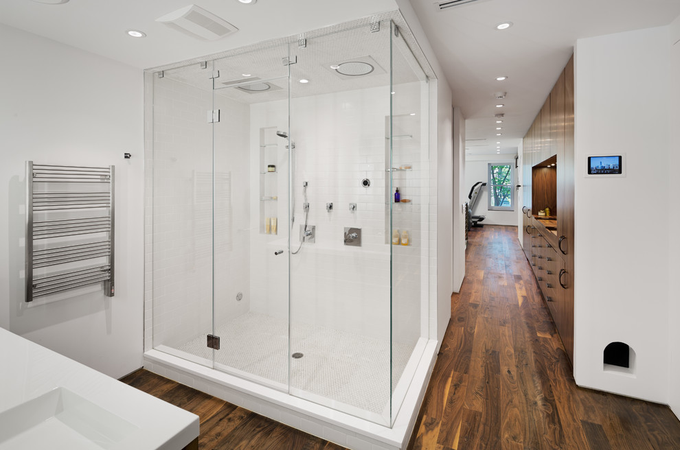 На фото: главная ванная комната среднего размера в современном стиле с плоскими фасадами, темными деревянными фасадами, двойным душем, белой плиткой, керамогранитной плиткой, белыми стенами, темным паркетным полом и монолитной раковиной