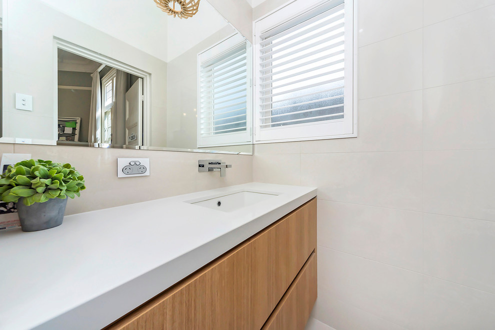 Ejemplo de cuarto de baño tradicional renovado con armarios con paneles lisos, puertas de armario de madera clara, baldosas y/o azulejos blancos, paredes blancas, lavabo bajoencimera y encimera de granito