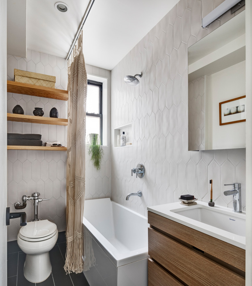 Photo of a contemporary bathroom in New York with flat-panel cabinets, dark wood cabinets, a corner bath, a shower/bath combination, white tiles, ceramic tiles, white walls, light hardwood flooring, a submerged sink, engineered stone worktops, black floors, a shower curtain, white worktops and a single sink.