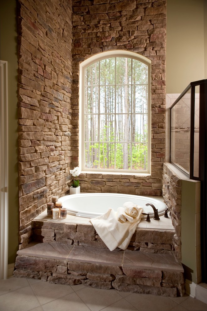 На фото: большая главная ванная комната в классическом стиле с ванной в нише, каменной плиткой, бежевыми стенами, полом из керамической плитки и бежевым полом с
