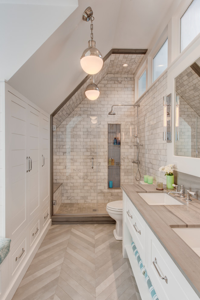 Bild på ett lantligt grå grått badrum med dusch, med luckor med upphöjd panel, vita skåp, en dusch i en alkov, vit kakel, vita väggar, ett undermonterad handfat, grått golv och dusch med gångjärnsdörr