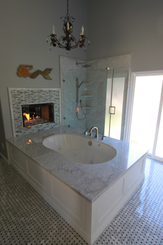 This is an example of a large classic ensuite bathroom in Los Angeles with a submerged sink, shaker cabinets, white cabinets, marble worktops, a submerged bath, a built-in shower, a one-piece toilet, white tiles, glass sheet walls, grey walls and mosaic tile flooring.