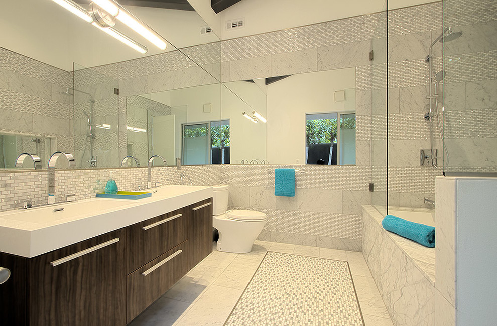 Modelo de cuarto de baño retro con armarios con paneles lisos, puertas de armario de madera en tonos medios, bañera empotrada, combinación de ducha y bañera, baldosas y/o azulejos blancos y baldosas y/o azulejos en mosaico