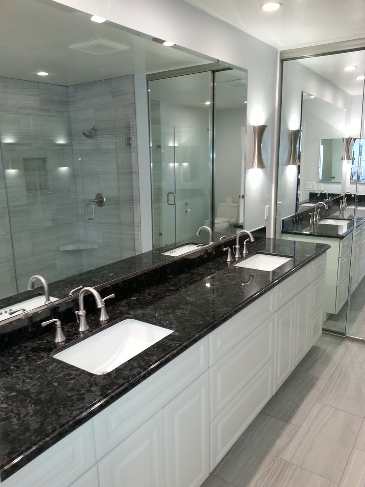 Idéer för ett klassiskt badrum, med ett undermonterad handfat, luckor med upphöjd panel, vita skåp, granitbänkskiva, grå kakel, stenhäll, grå väggar och travertin golv