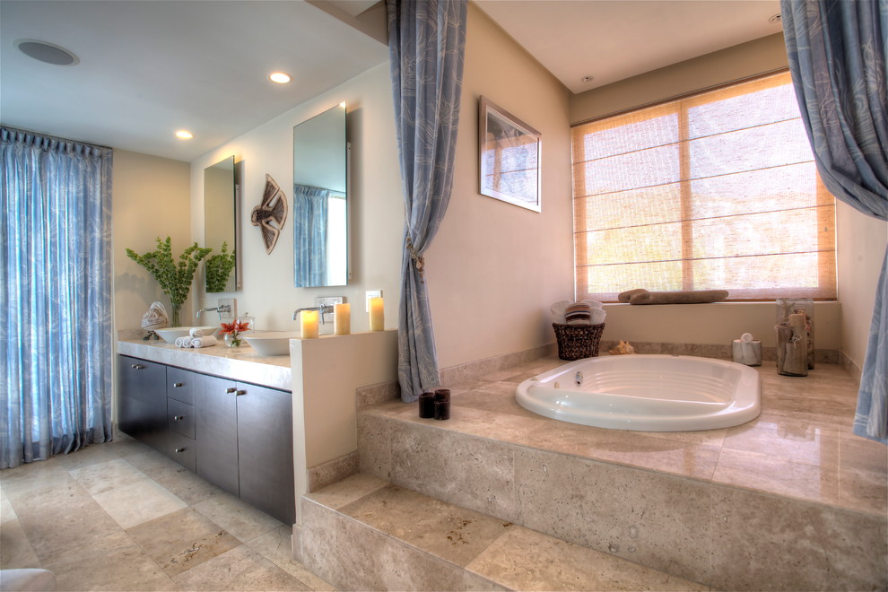 Inspiration for a timeless master ceramic tile and brown floor drop-in bathtub remodel in Orange County with flat-panel cabinets, dark wood cabinets, beige walls and a vessel sink