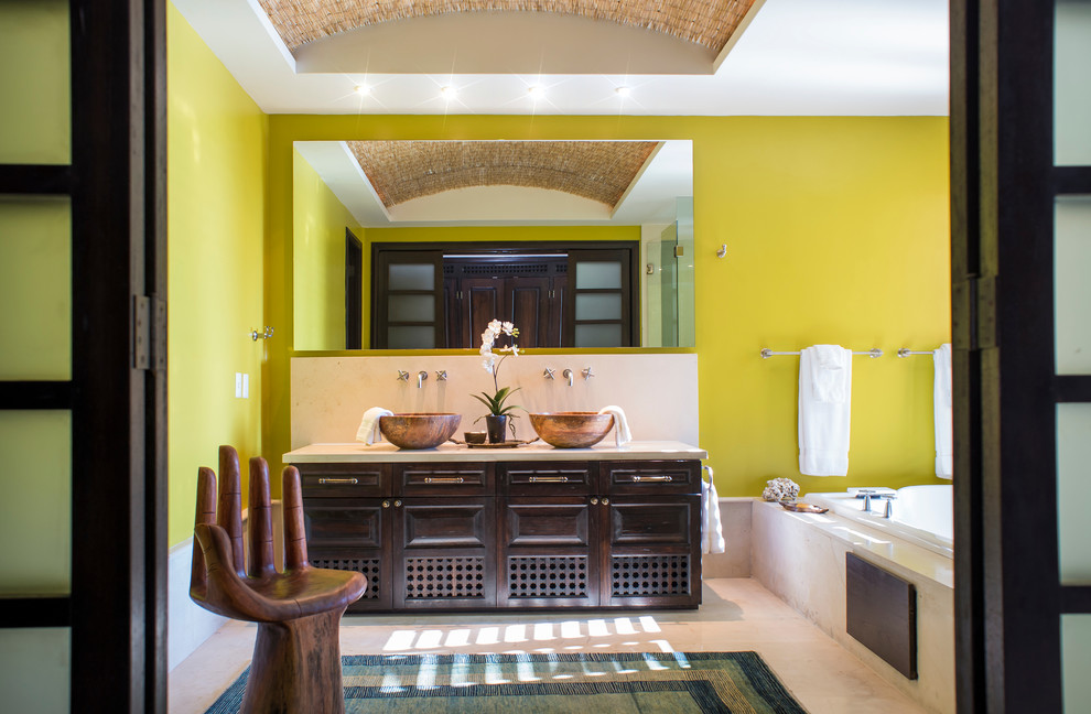 На фото: главная ванная комната среднего размера в морском стиле с настольной раковиной, темными деревянными фасадами, накладной ванной, желтыми стенами, белой плиткой, керамогранитной плиткой, мраморным полом и фасадами с выступающей филенкой