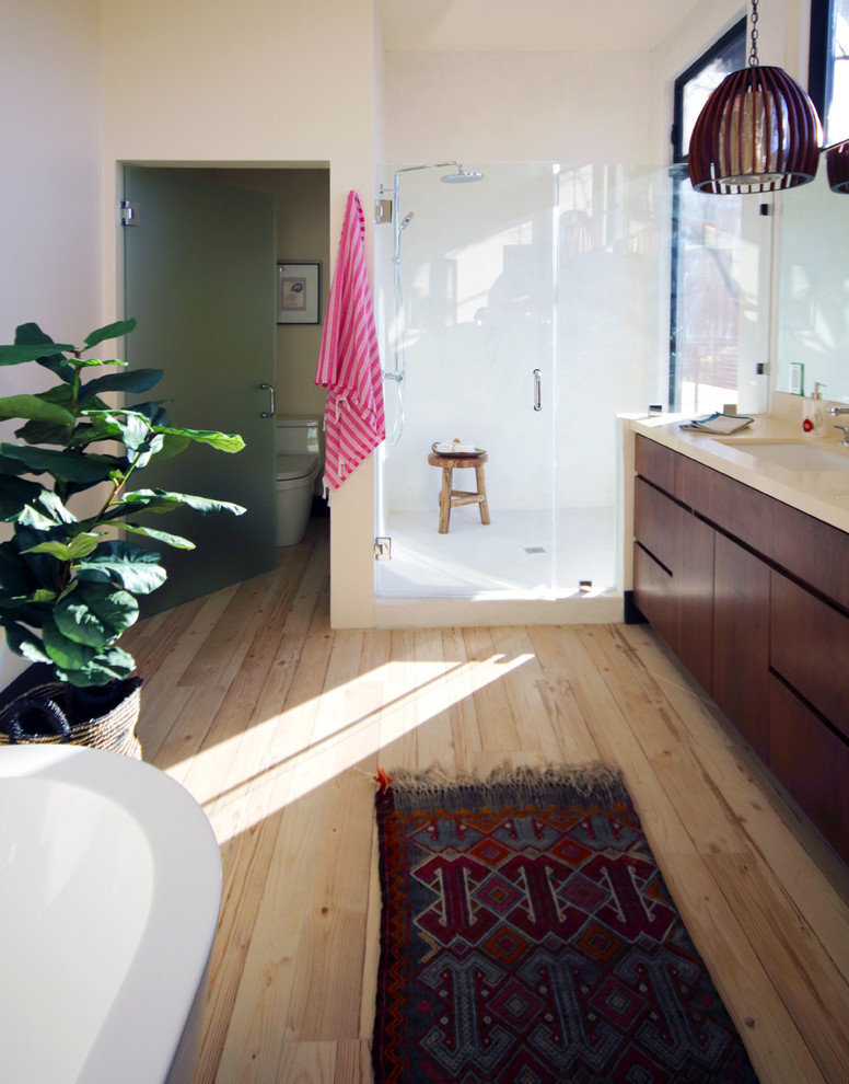 Idéer för mellanstora eklektiska en-suite badrum, med släta luckor, bruna skåp, ett fristående badkar, en öppen dusch, en toalettstol med hel cisternkåpa, vit kakel, vita väggar, mellanmörkt trägolv, ett undermonterad handfat, bänkskiva i kalksten, beiget golv och dusch med gångjärnsdörr