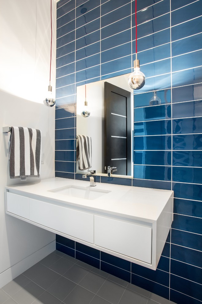 Inspiration pour une salle de bain design avec un placard à porte plane, des portes de placard blanches, un carrelage bleu, un mur blanc, un lavabo encastré et un sol gris.