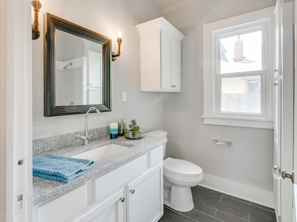 Example of a mid-sized classic 3/4 ceramic tile and gray floor bathroom design in Oklahoma City with shaker cabinets, white cabinets, a two-piece toilet, gray walls, an undermount sink and granite countertops