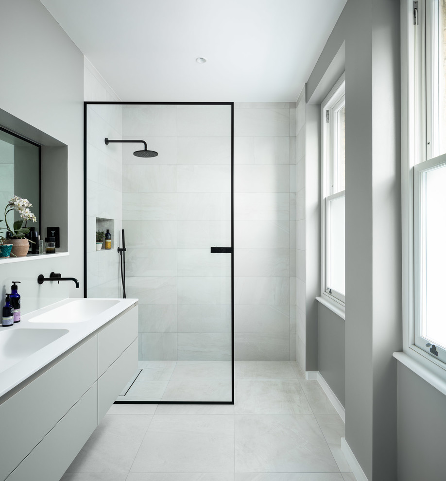 Cette image montre une salle d'eau grise et noire design avec un placard à porte plane, des portes de placard grises, une douche à l'italienne, un carrelage gris, un mur gris, un lavabo intégré, un sol gris, aucune cabine, un plan de toilette blanc et une fenêtre.