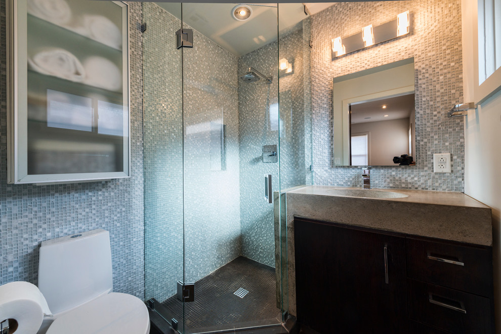 Small modern shower room bathroom in Other with an integrated sink, grey cabinets, concrete worktops, a corner shower, a one-piece toilet, white tiles, mosaic tiles, white walls, porcelain flooring and flat-panel cabinets.