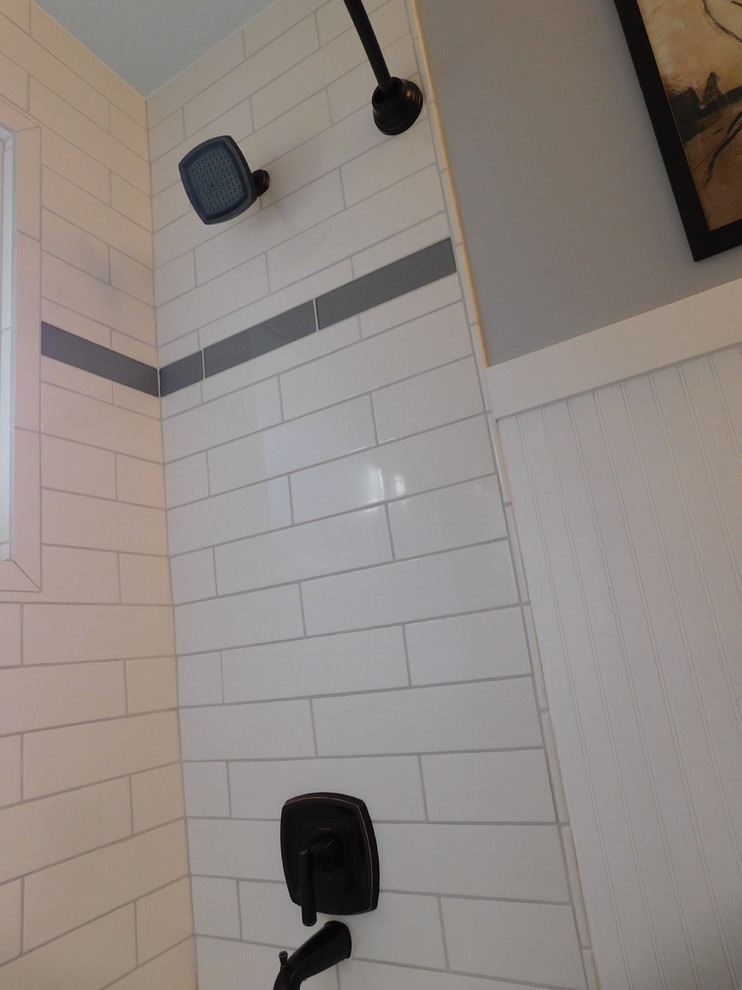 Bild på ett litet maritimt en-suite badrum, med möbel-liknande, bruna skåp, ett badkar i en alkov, en dusch i en alkov, en toalettstol med separat cisternkåpa, vit kakel, keramikplattor, grå väggar, vinylgolv, ett fristående handfat, bänkskiva i kvarts, brunt golv och dusch med duschdraperi