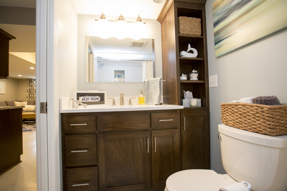 Modern inredning av ett litet badrum, med ett undermonterad handfat, skåp i shakerstil, skåp i mellenmörkt trä, granitbänkskiva, ett badkar i en alkov, en dusch/badkar-kombination, en toalettstol med separat cisternkåpa, vit kakel, porslinskakel och grå väggar
