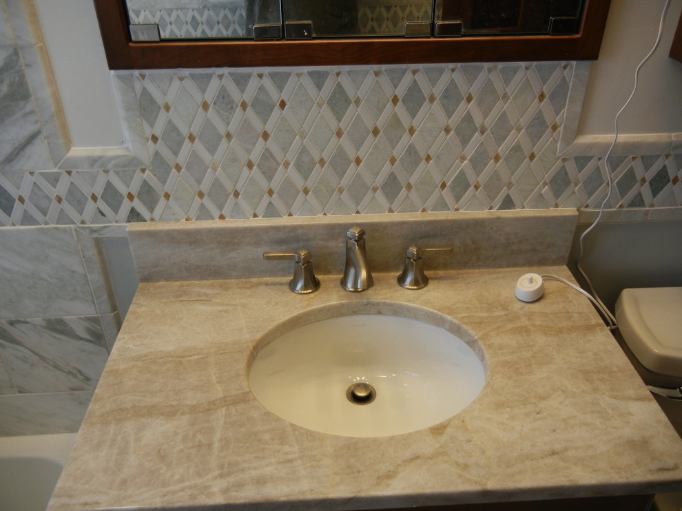 Exempel på ett litet klassiskt en-suite badrum, med luckor med upphöjd panel, skåp i mörkt trä, ett badkar i en alkov, en dusch/badkar-kombination, en toalettstol med separat cisternkåpa, grön kakel, stenkakel, marmorgolv, ett undermonterad handfat och bänkskiva i kvartsit