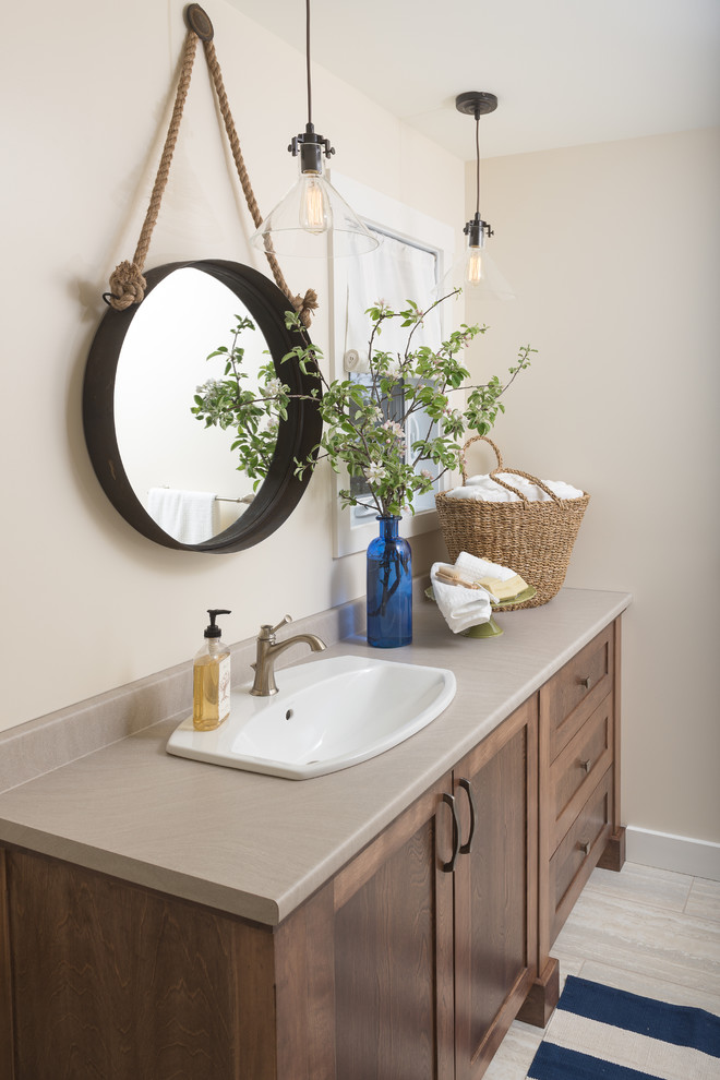 Immagine di una stanza da bagno costiera con lavabo da incasso, ante in stile shaker, ante in legno bruno, pareti beige, pavimento con piastrelle in ceramica e top grigio