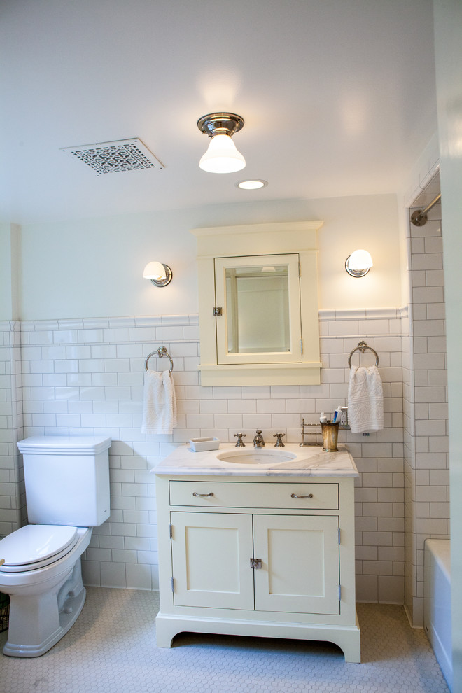 Пример оригинального дизайна: ванная комната: освещение в классическом стиле с врезной раковиной, фасадами в стиле шейкер, раздельным унитазом, белой плиткой, плиткой кабанчик и желтыми фасадами