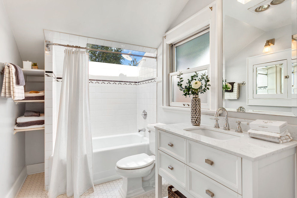 Cette image montre une grande salle de bain principale craftsman avec des portes de placard blanches, un combiné douche/baignoire, un carrelage blanc, un sol en carrelage de céramique, un sol blanc, une cabine de douche avec un rideau, un plan de toilette blanc, une baignoire en alcôve, WC séparés, des carreaux de céramique, un mur gris, un lavabo encastré, une fenêtre et un placard avec porte à panneau encastré.