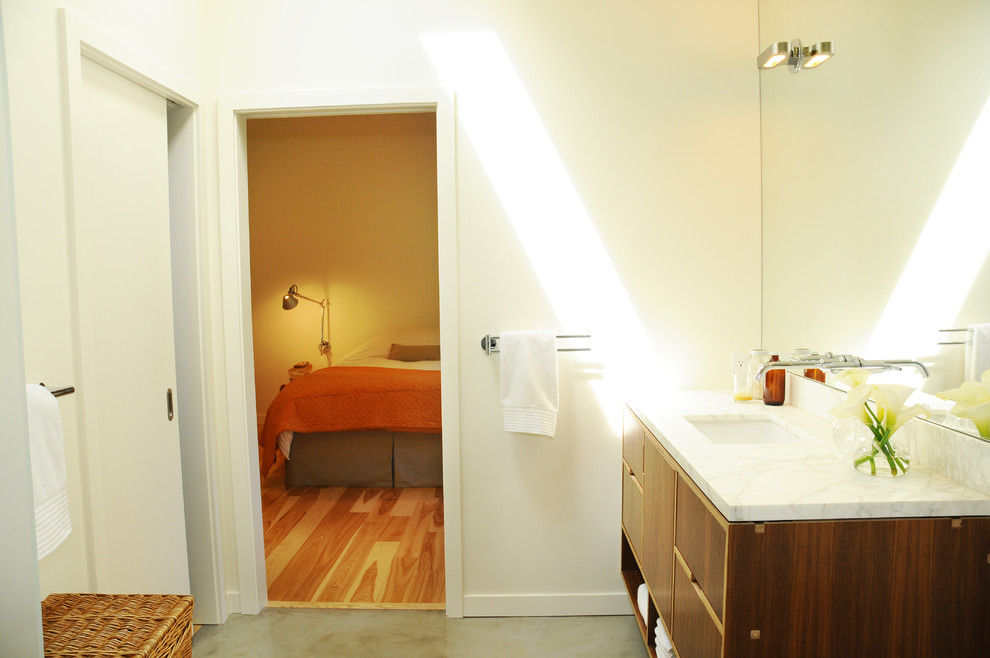 Foto de cuarto de baño retro con lavabo integrado, armarios con paneles lisos, puertas de armario de madera en tonos medios y encimera de mármol