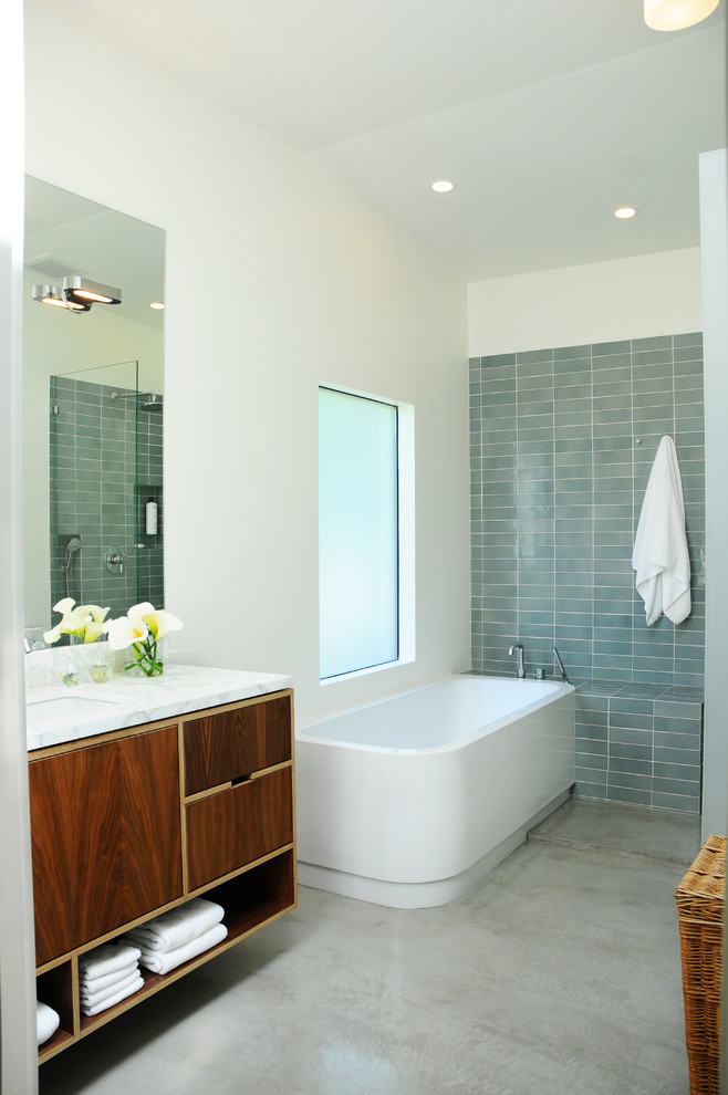 Foto di una stanza da bagno moderna con lavabo integrato, ante lisce, ante in legno bruno, top in marmo, vasca freestanding, doccia ad angolo, WC a due pezzi, piastrelle blu e piastrelle in ceramica