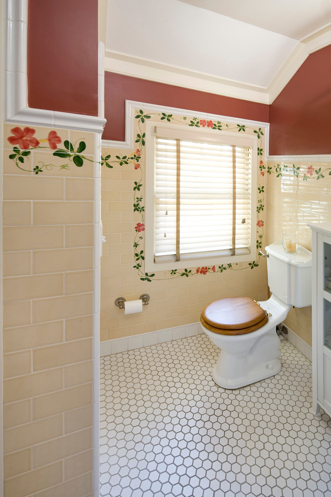 Klassisches Badezimmer mit gelben Fliesen, weißen Schränken, Wandtoilette mit Spülkasten, Keramikfliesen, brauner Wandfarbe und Mosaik-Bodenfliesen in Santa Barbara